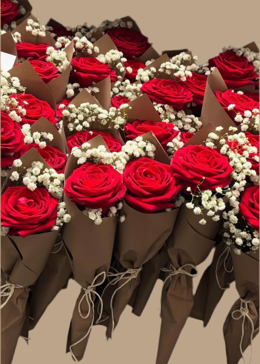 Bouquets of red roses with white flowers in brown paper cones on a beige background