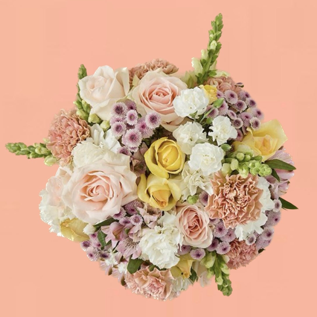 Peach and cream flower arrangement with roses, carnations, alstroemeria, and snapdragons in a vase — playful and elegant bouquet.