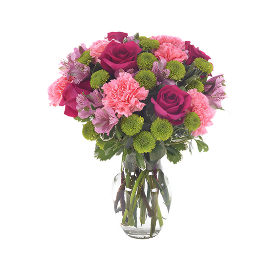 A glass vase containing an arrangement of pink and pale pink flowers, including roses and alstroemeria.