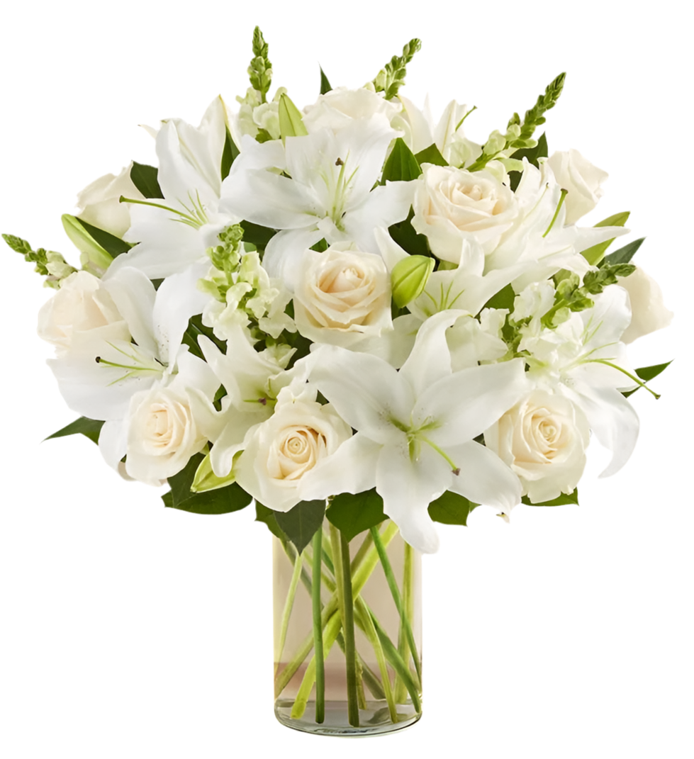 A bouquet of white roses, lilies, and stock flowers arranged in a clear vase.