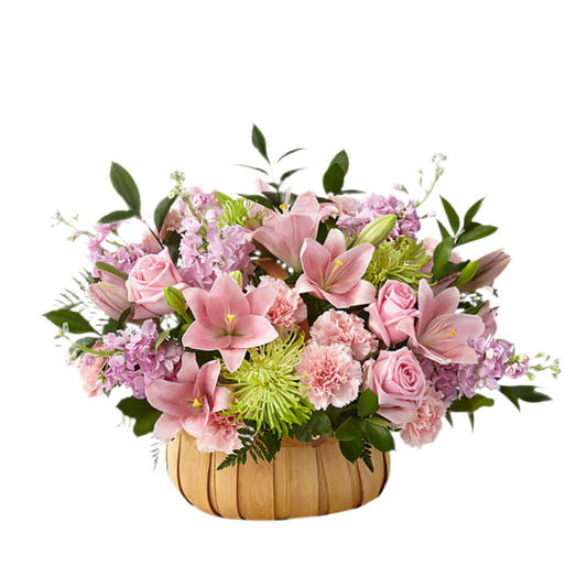A bouquet of flowers including pink carnations, green stock, pink roses, white lilies, and purple Fuji mums, arranged in a wooden basket.