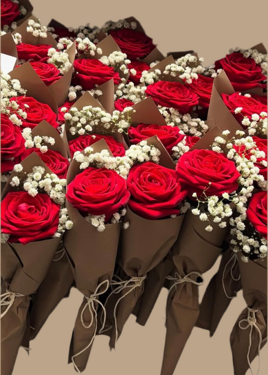 Bouquets of red roses with white flowers in brown paper cones on a beige background