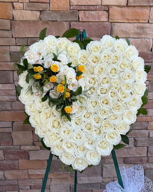Heart-shaped floral arrangement made of white roses with small yellow roses and green foliage. FUNERAL FLOWERS delivered in Gilbert, Chandler, Mesa, Tempe, Queen creek, Phoenix